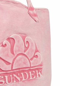 Sac fourre-tout en tissu rose avec un design texturé arborant un motif de soleil et le mot "SUNDEK" en relief en bas. Les poignées sont intégrées au sac.
