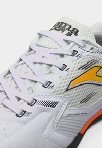 Λευκό αθλητικό παπούτσι με λευκά κορδόνια, κίτρινο λογότυπο, επάνω μέρος από δίχτυ και κείμενο που αναδεικνύει το σύστημα αερισμού και τα χαρακτηριστικά της τέλειας εφαρμογής.