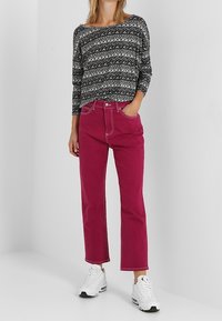 Zwart-wit gestreepte lange mouwen top gecombineerd met hoge taille, taps toelopende fuchsia broek en witte sneakers. Eenvoudig, modern design.