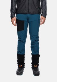 Blauwe technische broek met een zwart zakpaneel, elastische boorden en versterkte onderdelen. Gemaakt om te dragen met zwarte skibotten.