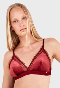 Soutien-gorge bordeaux avec un design de coque triangulaire, ornements en dentelle, tissu doux, bretelles réglables et une bande en bas.