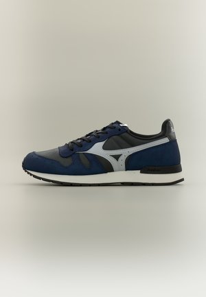 Μπλε και μαύρο αθλητικό παπούτσι με άσπρη μεσαία σόλα, μαύρη εξωτερική σόλα, μαύρα κορδόνια και γκρι λογότυπο στο πλάι, εμφανίζεται σε προφίλ σε ουδέτερο φόντο.