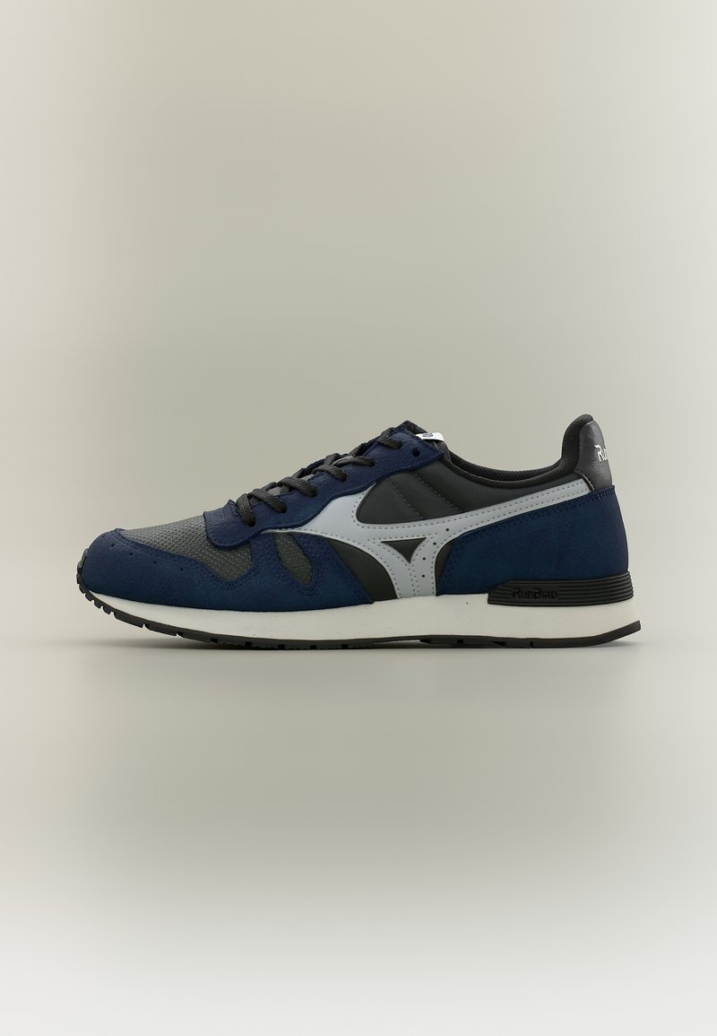 Μπλε και μαύρο αθλητικό παπούτσι με άσπρη μεσαία σόλα, μαύρη εξωτερική σόλα, μαύρα κορδόνια και γκρι λογότυπο στο πλάι, εμφανίζεται σε προφίλ σε ουδέτερο φόντο.