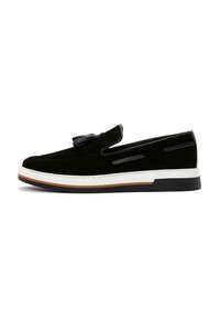 Black suede slip-on shoe with a white midsole, stitched detailing, and a rubber outsole. Features a decorative tassel on the vamp.