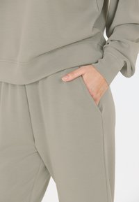 Ljust grått, mjukt tyg loungewear-set. T-shirten har en bekväm passform, medan byxorna har sidfickor och en lös, avslappnad silhuett.