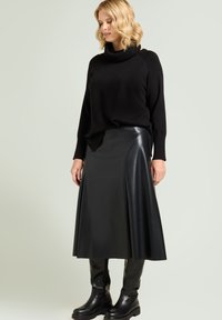 Sort strikket rullekravesweater kombineret med en sort læder A-formet nederdel og knæhøje sorte støvler; glatte teksturer og en slank silhuet.