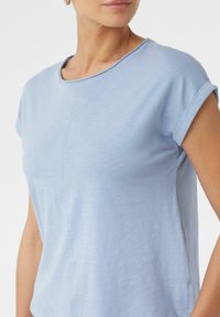 Jasnoniebieski t-shirt z krótkim rękawem, wykonany z miękkiego materiału, z okrągłym dekoltem i podszytymi rękawami, z detalem szwu na przodzie.