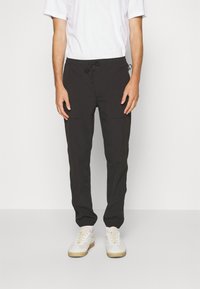 Černé tapered joggingové kalhoty s elastickým pasem a šňůrkou. Mají boční kapsy a hladkou, lehkou tkaninu.