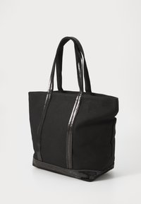 Tote bag en toile noire avec des accents métalliques brillants et deux poignées robustes, présentant un intérieur spacieux et un panneau inférieur texturé.