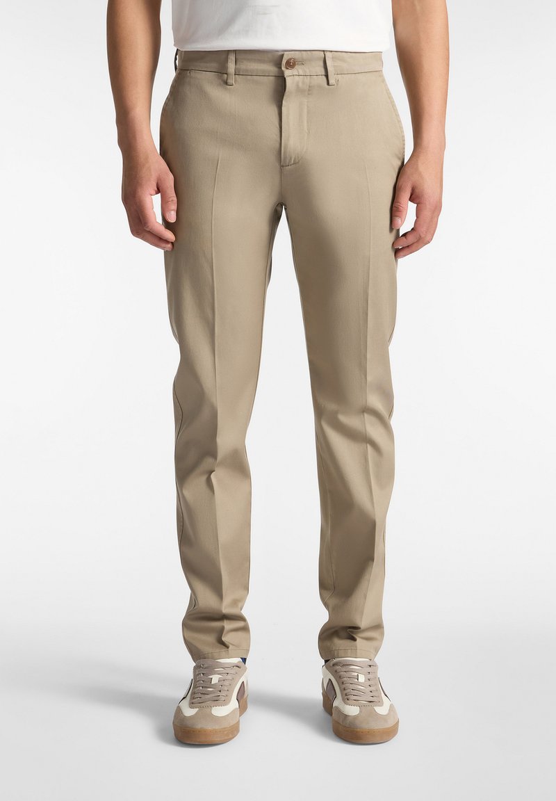 Bež hlače iz gladkega blaga s slim fit krojem, z sprednjimi gubami, enim gumbom za zapiranje in stranskima žepoma. Združene z lahkimi supergami.