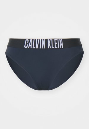Marineblauwe bikini onderkant met een gladde textuur. Heeft een zwarte tailleband met witte "CALVIN KLEIN" branding. Eenvoudig en klassiek ontwerp.