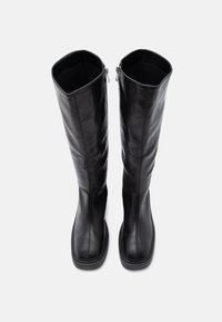 Μαύρες μπότες έως το γόνατο από λείο δέρμα, με φερμουάρ στο πλάι και ορθογώνιο σχήμα στα δάχτυλα. Διακριτική ραφή.