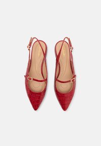Chaussures slingback rouges à bout pointu avec texture crocodile, bride de cheville et petite boucle. Semelle intérieure rembourrée avec des détails perforés.