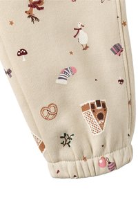 Beige stof med finurlige mønstre af svampe, vanter, en and, kringler og pynt, med en detaljeret foldet manchet.