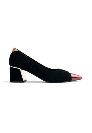 Escarpin en daim noir avec un bout pointu rouge contrastant et un accent métallique sur le talon bloc. Texture lisse avec des lignes épurées.