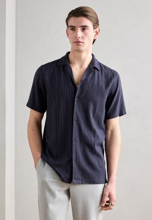 Korte mouwen button-up shirt in donker marineblauw met witte verticale strepen, gemaakt van zachte stof, met een ontspannen kraag en subtiele glans.
