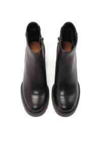 Botas de tobillo de cuero negro con un acabado suave, punteras redondas y cremalleras en los laterales. Suelas de goma texturizadas y tacones bajos apilados.
