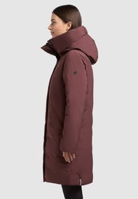 Bordo toonist talvejope kõrge krae ja kapuutsiga, sileda tekstuuriga, ees lukuga ja küljetaskutega lisafunktsionaalsuse jaoks.