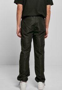 Pantalones negros, ligeros y ligeramente brillantes con un corte relajado. Cuentan con una cintura elástica y cuerdas ajustables en los tobillos.