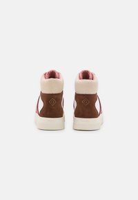 Pair of high-top sneakers with brown suede heel, cream collar, pink inner lining, and white sole, viewed from the back on a white background.