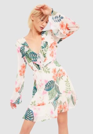 Abito floreale in tessuto leggero e trasparente con scollo a V e maniche lunghe a campana. Caratterizzato da una combinazione di fiori rosa e foglie verdi.