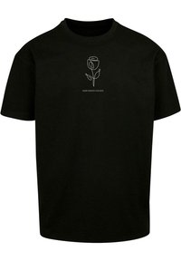 Camiseta de manga corta negra con un diseño de rosa dibujada en línea blanca y el texto "CULTIVA PENSAMIENTOS POSITIVOS" debajo, hecha de material de algodón.