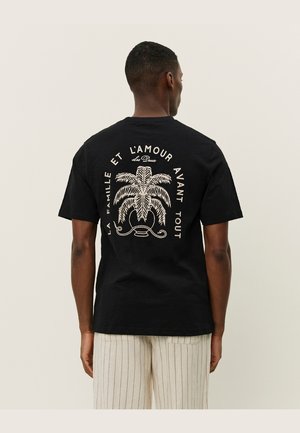 Black cotton t-shirt featuring a large white palm tree graphic and text design on the back, crew neck, and short sleeves.