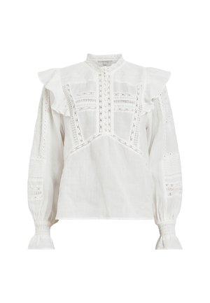 Blouse blanche à manches longues en tissu léger, ornée de volants, de détails en dentelle, de fermetures à boutons et de poignets froncés. Design texturé.