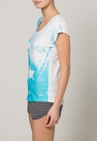 Camiseta de manga corta con un patrón de estrellas azul y blanco y un diseño de escote en V. Fabricada con tejido ligero, tiene un corte relajado.