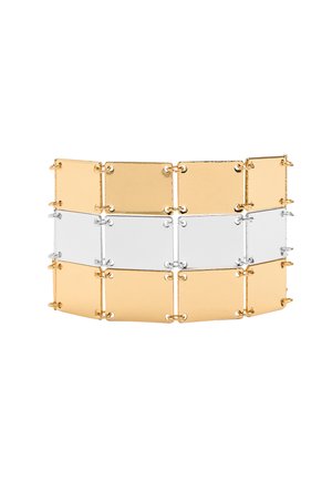 Szeroka bransoleta złożona z trzech rzędów połączonych prostokątnych metalowych płytek w tonacjach złota i srebra na białym tle.