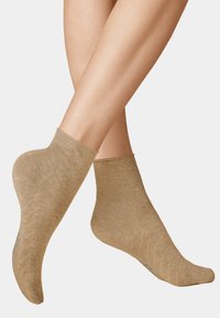 Beige Knöchelsocken aus weichem Stoff, mit einer glatten Oberfläche und einem dezenten Rippmuster entlang des Knöchels.
