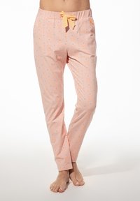 Lichtroze pyjamabroek met een elastische tailleband, een geknoopte gele strik en verspreide oranje en grijze stippenpatronen overal.