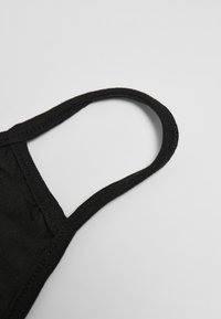 Svart tygmask med rundad överkant och elastiska öronloopar, med en slät yta och sydda sömmar.