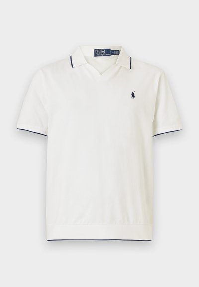 Bela polo majica z mornarsko modrim robom in kratkimi rokavi. Ima V-izrez in majhen vezen znak na prsih. Narejena je iz gladkega blaga.