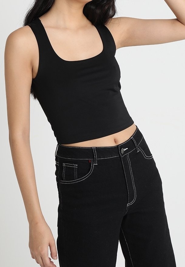 Czarny skrócony top na ramiączkach z kwadratowym dekoltem, wykonany z gładkiego materiału. Połączony z czarnymi jeansami o wysokim stanie z kontrastowymi szwami.