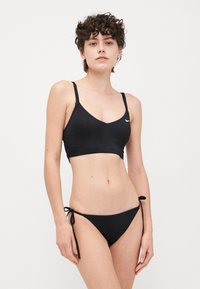 Black bikini set featuring a triangular bralette with adjustable straps and a matching bottom with side ties, made from smooth fabric.