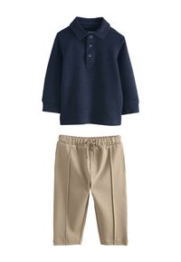 Polo bleu marine à manches longues avec trois boutons, associé à un pantalon beige à taille élastique doté de poches latérales et d'une coupe décontractée.