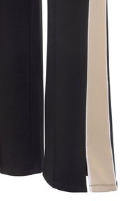 Schwarze und beige Sportpants mit einem seitlichen Panele-Design in einer kontrastierenden Farbe und weißem Piping entlang der Kanten. Weiche Textur sichtbar.