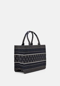 Torba tote w granatowym wzorze wykonana z teksturowanej tkaniny; posiada dwa mocne uchwyty oraz skomplikowane geometryczne wzory w odcieniu kremowym.