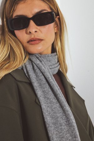 Svarta rektangulära solglasögon, grå stickad scarf och olivgrön kappa. Släta texturer och lagerdesign skapar ett elegant utseende.