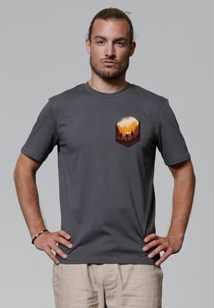 Grijze katoenen t-shirt met korte mouwen, voorzien van een grafische print van bergen en bomen in oranjetinten op de linkerbovenkant.