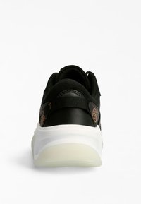 Baskets noires avec un panneau arrière texturé, présentant un accent marron. Semelle intermédiaire blanche épaisse avec une semelle extérieure légèrement transparente.
