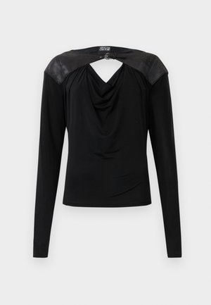 Black long-sleeve top with draped front, leather shoulder panels, and a small silver buckle at the back neckline.