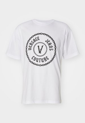 T-shirt en coton blanc avec un logo circulaire noir portant "VERSACE JEANS COUTURE" et un design central "V", entouré d'un motif de chaîne.