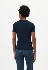 T-shirt bleu marine à manches courtes en tissu doux, avec un col rond classique et une silhouette ajustée.