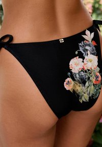 Zwarte bikinibroek met bloemenprint aan de linkerkant, met roze en witte bloemen en groene bladeren, en zijstrikdetails.