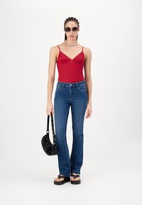 Punane bodysuit õhukeste rihmadega, sinised laiad teksad, mustad sandaalid, must käekott ja päikeseprillid. Tekstuur on sile; teksad on denimi.