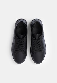 Black athletic shoes made of smooth leather with a rounded toe, flat laces, and side panel accent stripes. Treaded rubber soles.