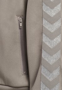 Szara sportowa kurtka z kieszenią na zamek błyskawiczny i srebrnym, teksturowanym wzorem w kształcie jodełki wzdłuż boku. Materiał wydaje się gładki i trwały.