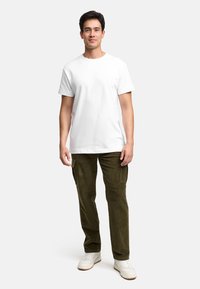 Hvit t-skjorte med rund hals, olivengrønne corduroy cargo bukser med sidelommer, og hvite joggesko. Enkel design med en avslappet passform.